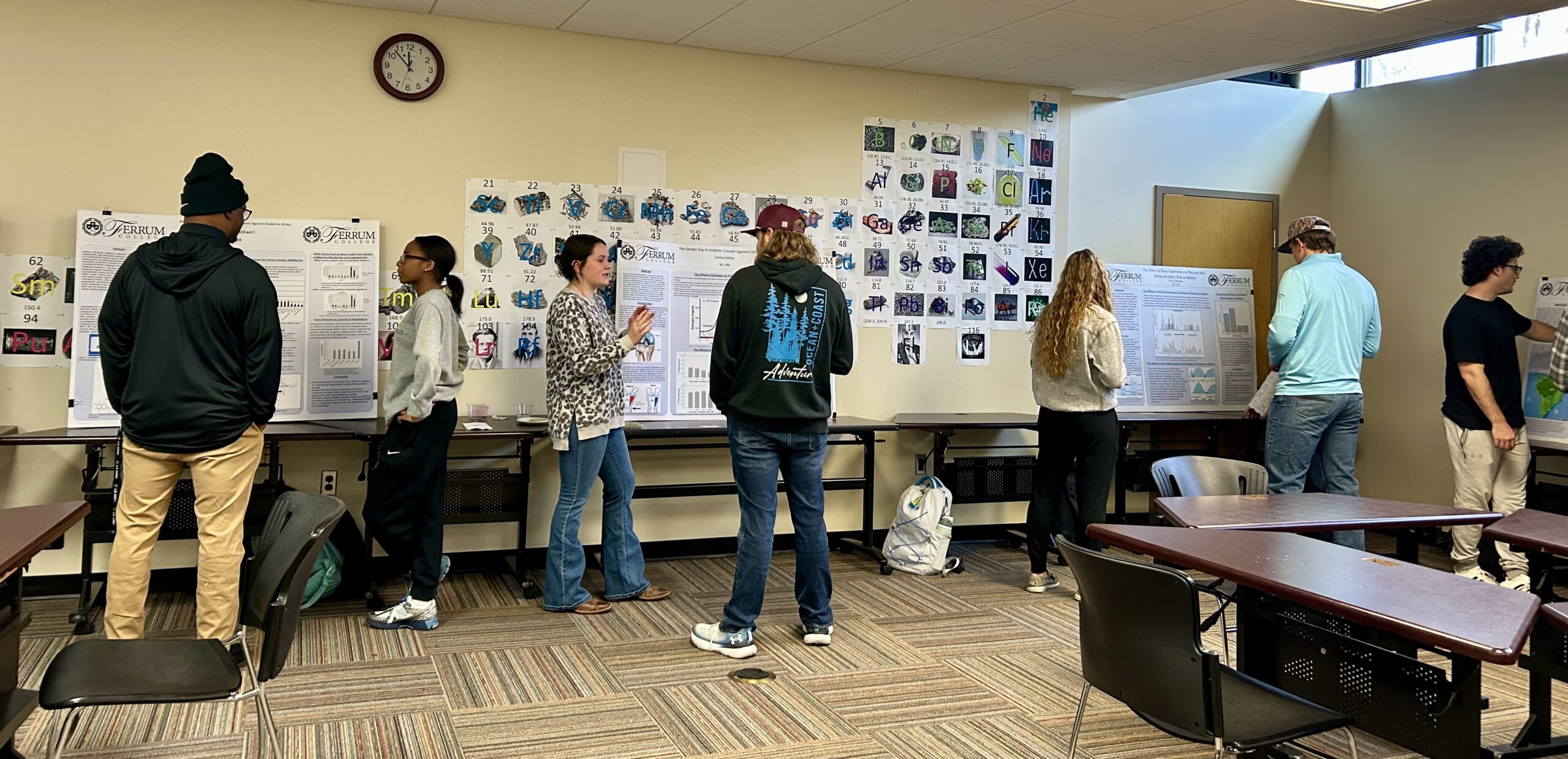 A row of science students showing each other their project posters along a wall in a classroom