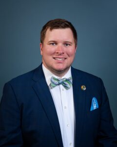 Headshot of alumnus Tyler Lee in dark suit, white shirt, and lighter blue bowtie, with short dark hair