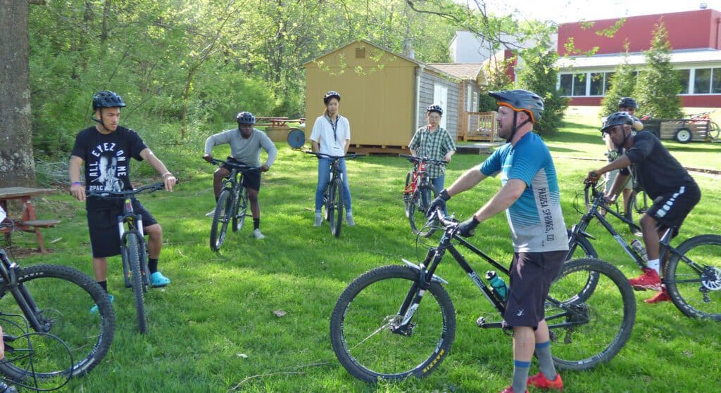 aaron conover talking to students on bicycles next to fitness center